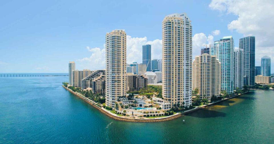 Miami skyline with modern high-rise buildings, a waterfront, and a clear sunny sky