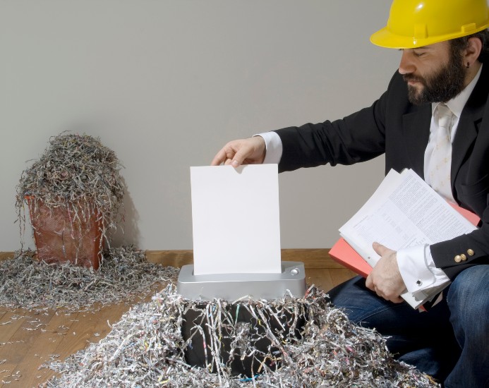 A Worker Feeds a Document into a Shredder During an On-Site Shredding Appointment in Miami, FL