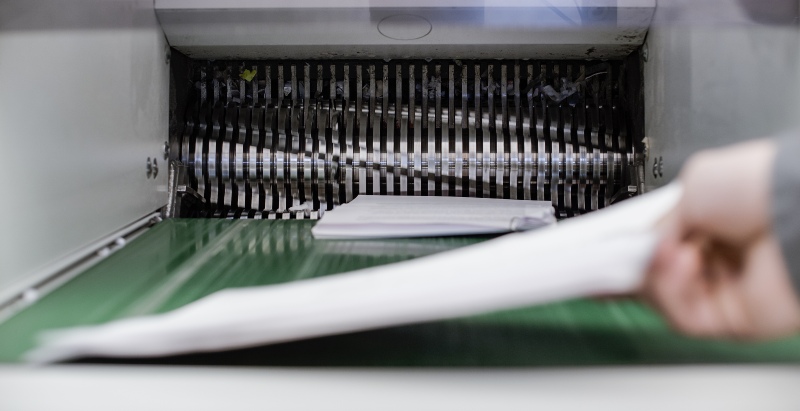 A Person Feeds Paper into a Shredding Machine for Document Destruction in Miami, FL